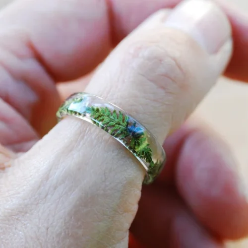 Close up of transparent resin ring showcasing delicate fern inclusion