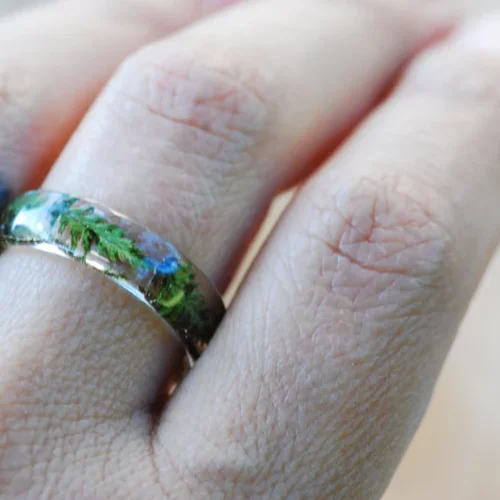 Hand wearing botanical resin ring with fern leaf inclusion – minimalist style jewelry