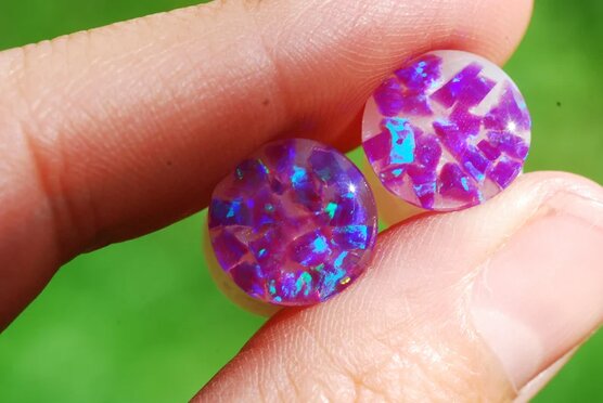 Hand holding Purple opal iridescent ear gauges