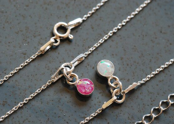 two bracelets with pink and white opal charms
