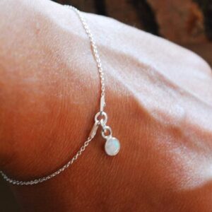 hand with bracelet made of white opal and silver chain