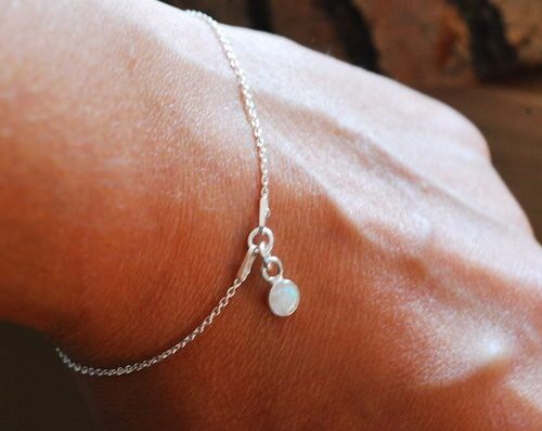 hand with bracelet made of white opal and silver chain