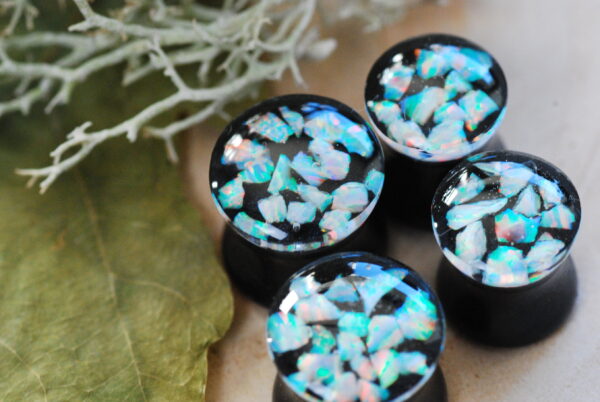 Iridescent white opal ear plugs made of resin in black color on the bottom and clear resin on the top