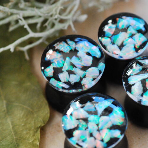 Iridescent white opal ear plugs made of resin in black color on the bottom and clear resin on the top