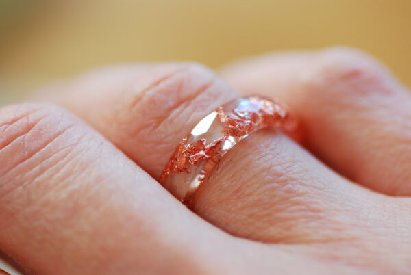 Clear faceted ring with copper flakes on finger