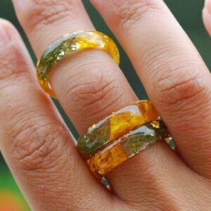 Clear resin ring made of yellow flowers, green moss and gold flakes