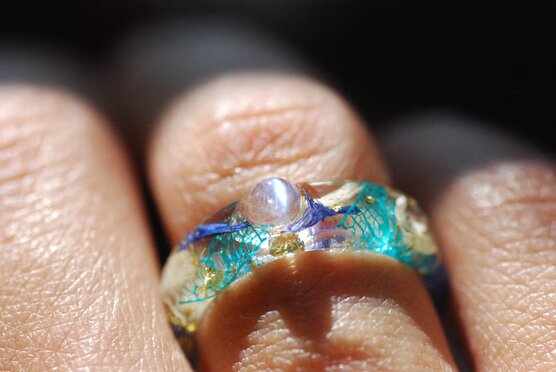 Rainbow moonstone with blue white flowers ring on finger