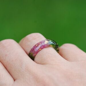 Natural red ruby gemstones with moss and metallic flakes set in a resin ring