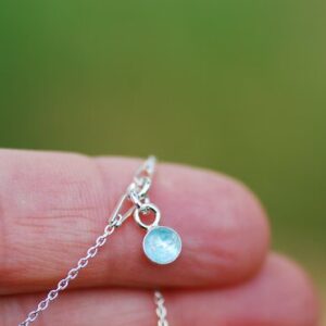 hand holding bracelet with aquamarine gemstone
