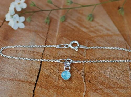 Silver bracelet with aquamarine lying on table