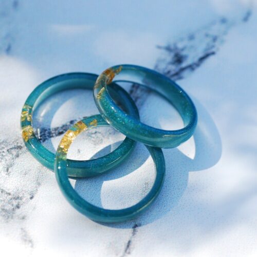 four blue green resin rings with gold