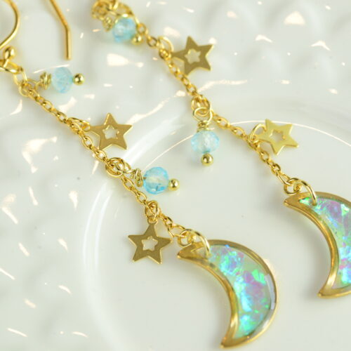 crescent moon earrings with stars and topaz lying on plate