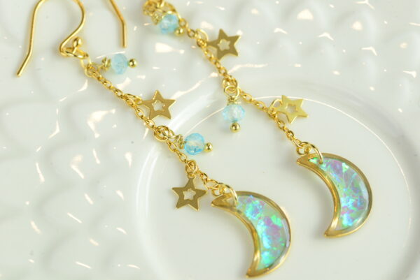 crescent moon earrings with stars and topaz lying on plate