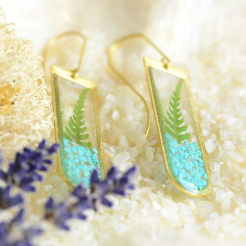 geometric earrings with fern and turquoise lying on plate