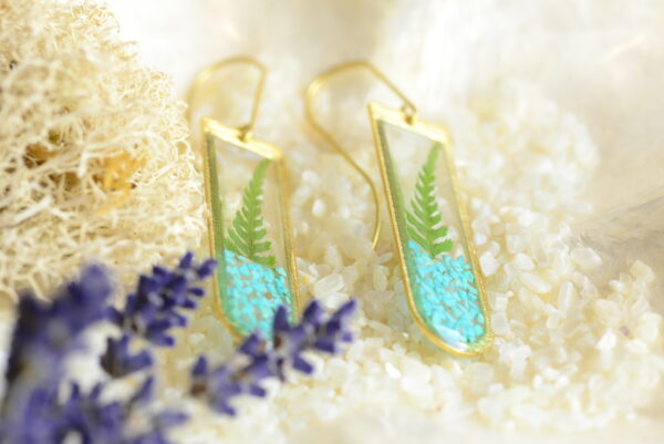 geometric earrings with fern and turquoise lying on plate