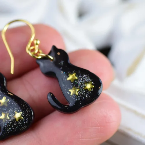 hand holding black cat earrings