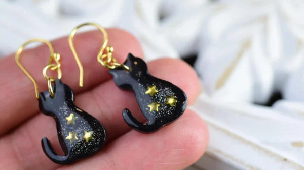 hand holding black cat earrings