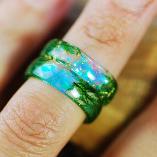 green moss aurora rings on finger