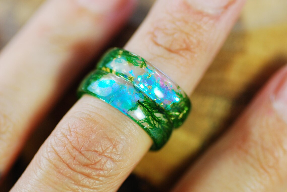 green moss aurora rings on finger