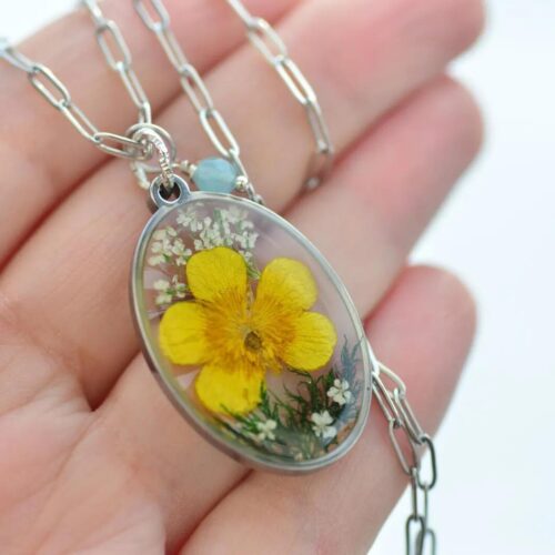 Hand showcasing flower pendant by AlpacaBlue